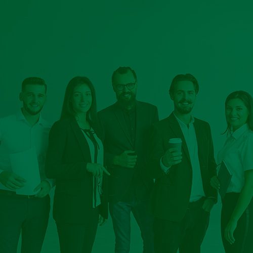Grupo de profissionais sorridentes posando para foto, vestindo roupas sociais e transmitindo um ambiente corporativo amigável e colaborativo.