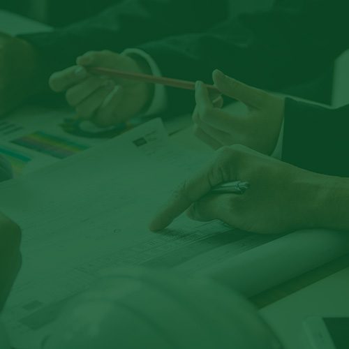 Pessoas analisando documentos e gráficos em uma mesa, representando educação em saúde e uso consciente do plano de saúde empresarial.