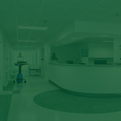 Imagem de recepção hospitalar com balcão curvo, corredores ao fundo e iluminação fluorescente, com filtro verde aplicado.