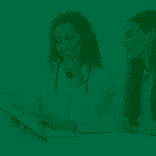 Duas médicas analisando um documento juntas, sorrindo e discutindo informações em um ambiente de consultório.