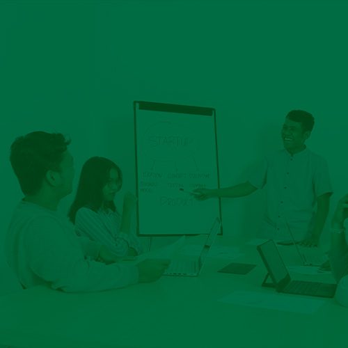 Equipe em reunião discutindo estratégias, com uma pessoa apresentando ideias em um quadro branco, representando ambiente corporativo ou startup.