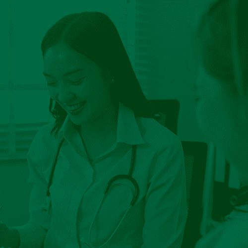 Dito pelo ChatGPT: Médica sorridente em consulta com paciente, usando estetoscópio e roupas de jaleco, representando atendimento humanizado e próximo.